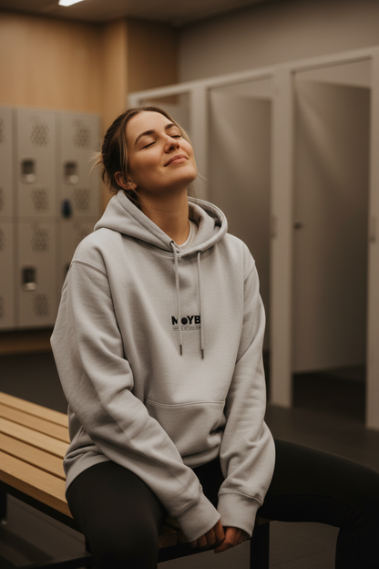 Person wearing a gray hoodie sitting in a locker room.